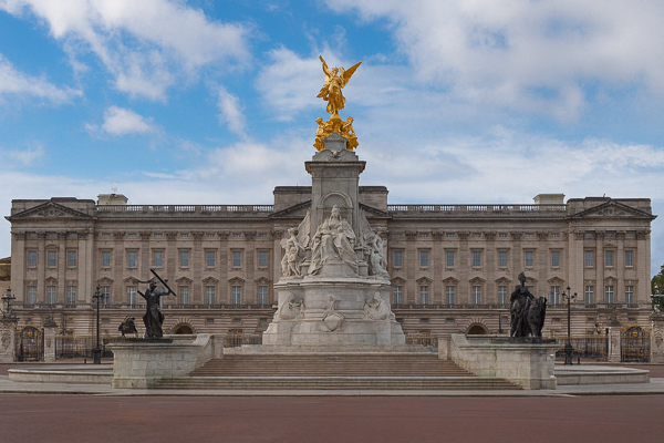 Buckingham Palace in London, UK, which serves as the official residence and administrative headquarters of the UK monarch. The foreground features the Victoria Memorial, a large monument dedicated to Queen Victoria, completed in 1914. 
